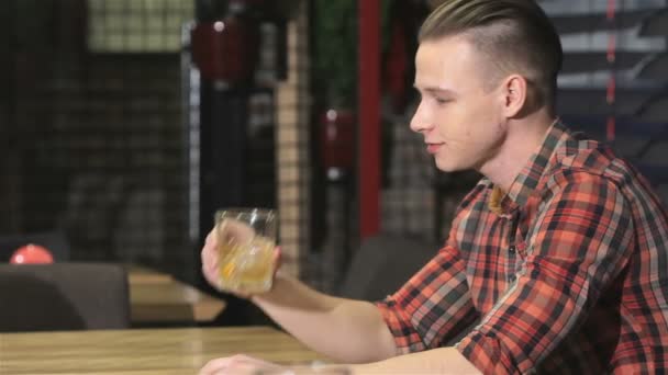 Blonde man drinkt alcohol aan de bar - Video