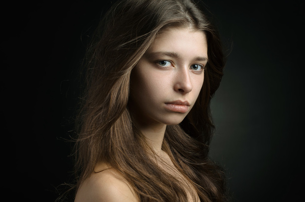 Dramatic portrait of a girl theme: portrait of a beautiful girl on a background in the studio - Zdjęcie, obraz