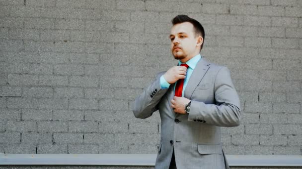 Young attractive businessman ajusting his tie and look at his watch - Кадри, відео