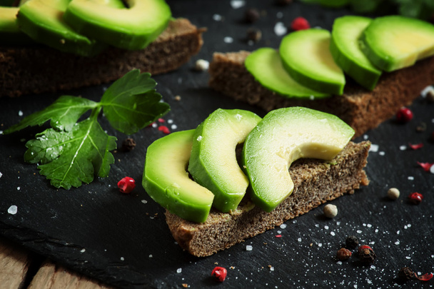 Sandwiches with avocado, black rye bread and spices - Фото, изображение