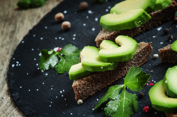 Sandwiches with avocado, black rye bread and spices - Foto, afbeelding