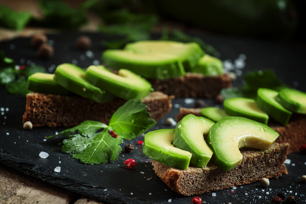 Sandwiches with avocado, black rye bread and spices - Photo, Image