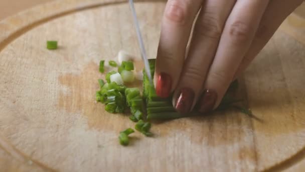 Girls hands with red nails cut green onions into slices - Video, Çekim