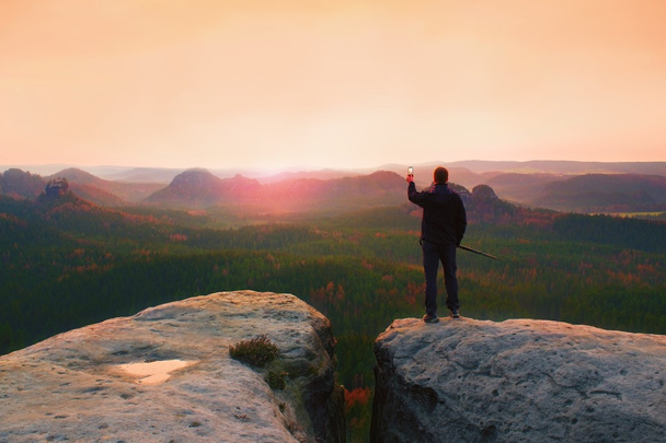Wanderer stehen mit Smartphone auf dem Gipfel des Berges und genießen den Frühlingssonnenaufgang. Reiseführer - Foto, Bild