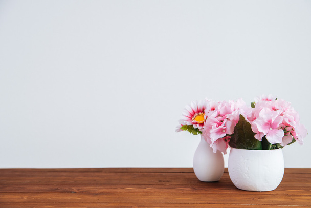 Bloemen op de houten tafel en witte muur - Foto, afbeelding