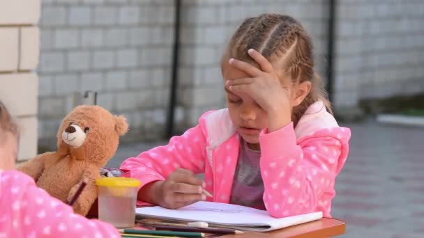 Επτά ετών κορίτσι ζωγραφισμένο του άλμπουμ δείχνει ένα άλλο παιδί, που ασχολούνται με την ζωγραφική με την αδελφή του στο δρόμο - Πλάνα, βίντεο
