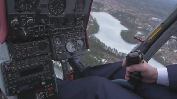 View at control system, pilot hold lever of helicopter. Camera inside. Above frozen river, forest - Footage, Video