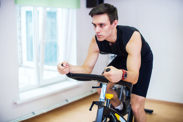 Athlete man biking in the gym  - Valokuva, kuva