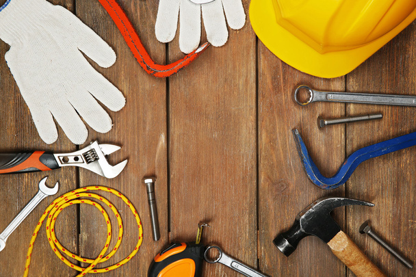 Working tools and yellow helmet on a wooden background. - Foto, immagini