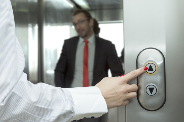 Female hand pressing elevator up button. Businessman inside of the elevator.  - Fotografie, Obrázek