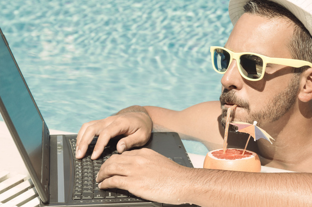 Young freelancer working on vacation next to the swimming pool - Foto, Bild