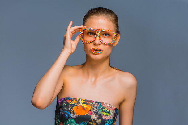Girl with candy sprinkles on lips ang glasses - Foto, Bild