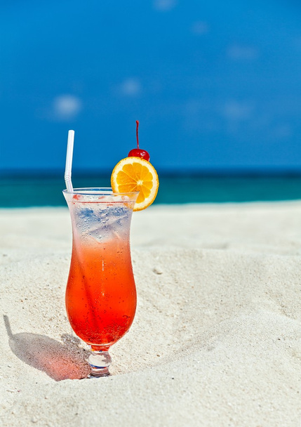 Стакан коктейля на песчаном коралловом пляже
 - Фото, изображение