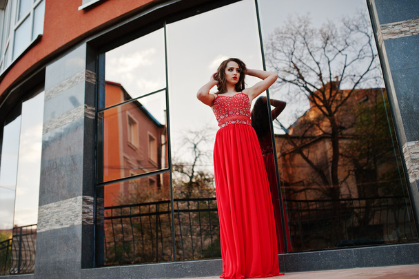 Portrait of fashionable girl at red evening dress posed backgrou - 写真・画像
