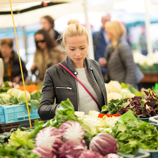 Vrouw koopt groente op de lokale voedselmarkt. - Foto, afbeelding
