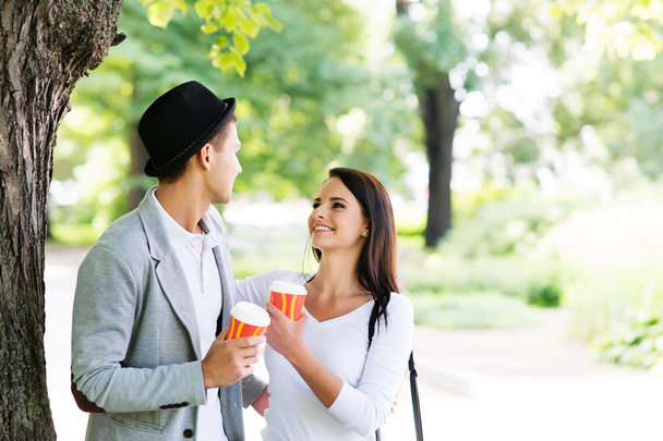 Young couple walking in the park together drinking coffee - Fotoğraf, Görsel