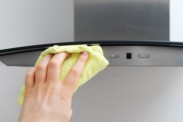 Man's hand wipes dust from exhaust hood. - Photo, Image