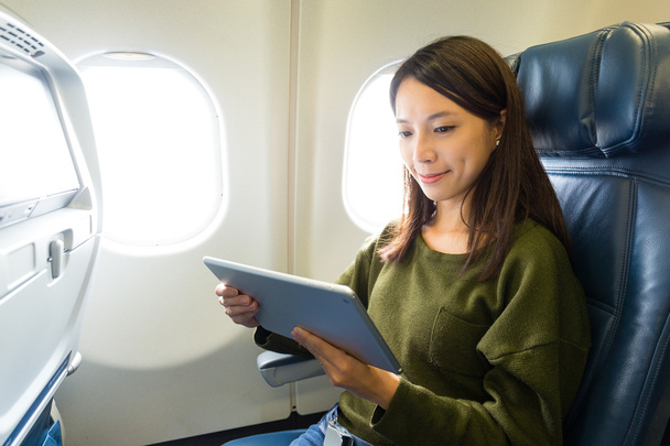 Frau benutzt Tablet-Computer im Flugzeug - Foto, Bild