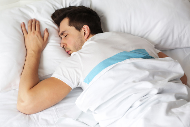 Young man sleeping on bed - Фото, изображение