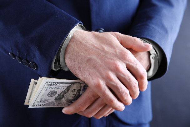 Man in handcuffs holding dollar banknotes, close up - Valokuva, kuva