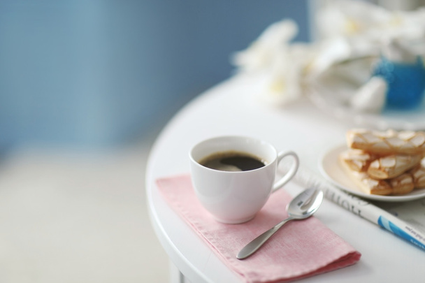 Cup of coffee with cookies on white table in light interior - Fotografie, Obrázek