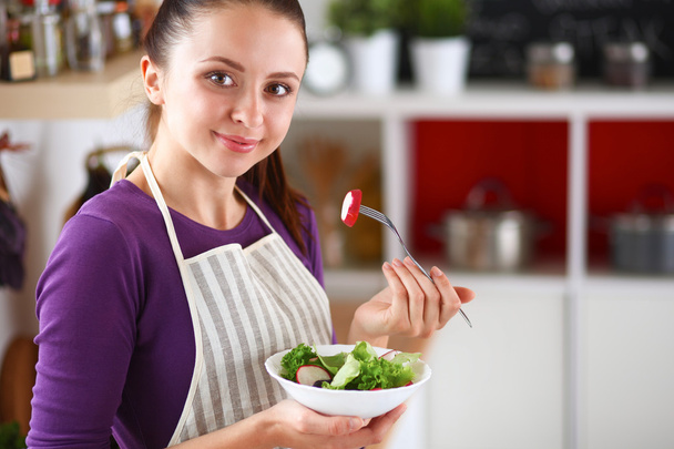 Young woman eating fresh salad in modern kitchen - Foto, imagen