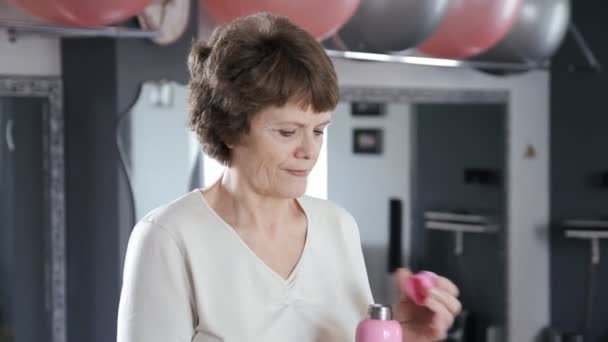 Retrato de la mujer mayor en la sala de fitness agua potable
 - Metraje, vídeo
