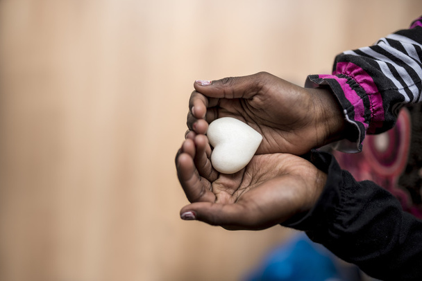 Primo piano di afro-americano ragazza in possesso di un marmo fatto cuore sha
 - Foto, immagini