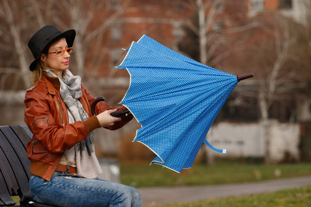 Nainen avaamassa sinistä sateenvarjoa
 - Valokuva, kuva