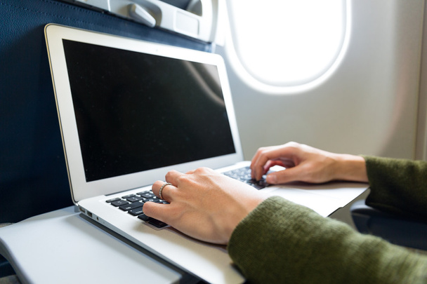 Женщина, работающая на ноутбуке в самолете
 - Фото, изображение