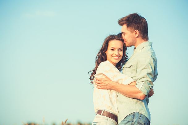 Young couple in love outdoor.Stunning sensual outdoor portrait of young stylish fashion couple posing in summer in field.Happy Smiling Couple in love.They are smiling and looking at each other - Foto, Imagem