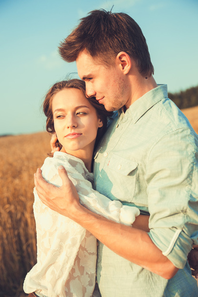 Young couple in love outdoor.Stunning sensual outdoor portrait of young stylish fashion couple posing in summer in field.Happy Smiling Couple in love.They are smiling and looking at each other - Фото, зображення