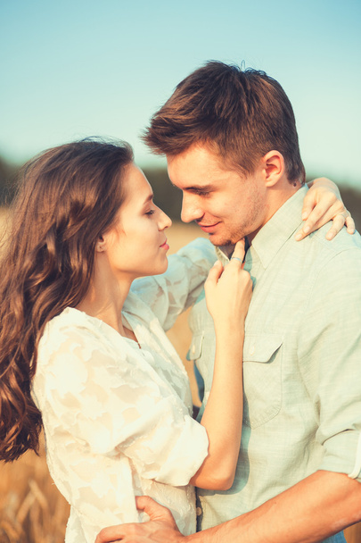 Young couple in love outdoor.Stunning sensual outdoor portrait of young stylish fashion couple posing in summer in field.Happy Smiling Couple in love.They are smiling and looking at each other - Photo, Image