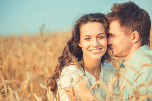 Young couple in love outdoor.Stunning sensual outdoor portrait of young stylish fashion couple posing in summer in field.Happy Smiling Couple in love.They are smiling and looking at each other - Фото, изображение
