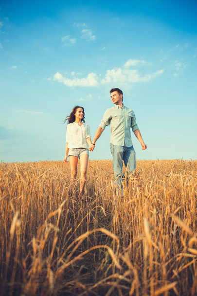 Young couple in love outdoor.Stunning sensual outdoor portrait of young stylish fashion couple posing in summer in field.Happy Smiling Couple in love.They are smiling and looking at each other - Fotografie, Obrázek