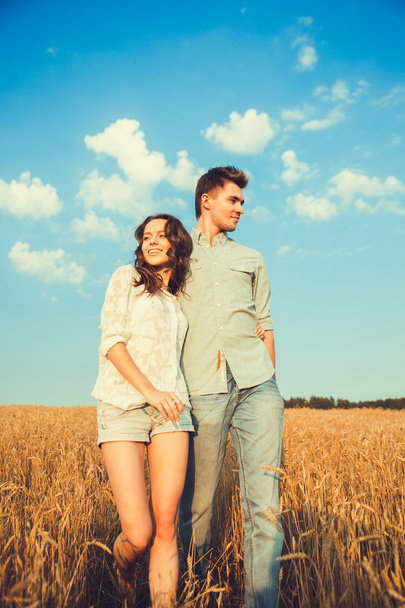 Young couple in love outdoor.Stunning sensual outdoor portrait of young stylish fashion couple posing in summer in field.Happy Smiling Couple in love.They are smiling and looking at each other - 写真・画像