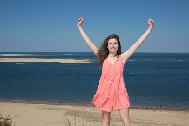 Happy woman enjoying relaxing breeze and freedom by the sea. Joyful asian girl raising arms to the sky. - Photo, Image