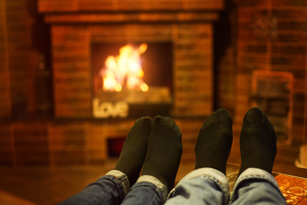 male and female legs near the fireplace. Family concept - Photo, Image