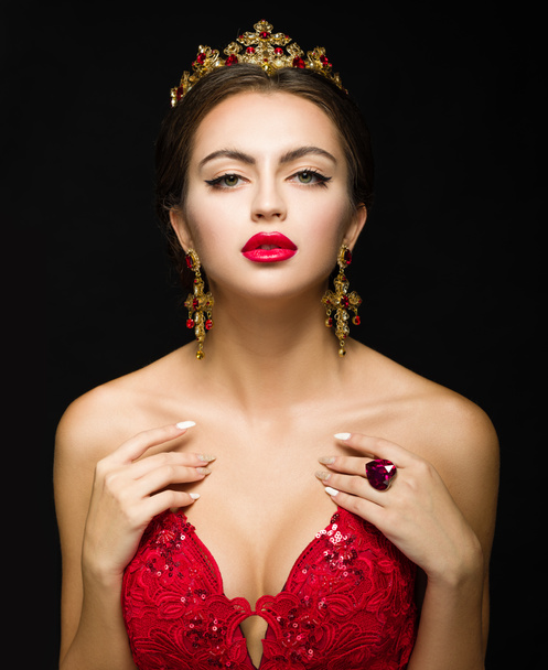 Beautiful girl in a golden crown and earrings on a dark backgrou - Photo, Image