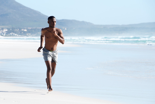 jonge man loopt op strand - Foto, afbeelding