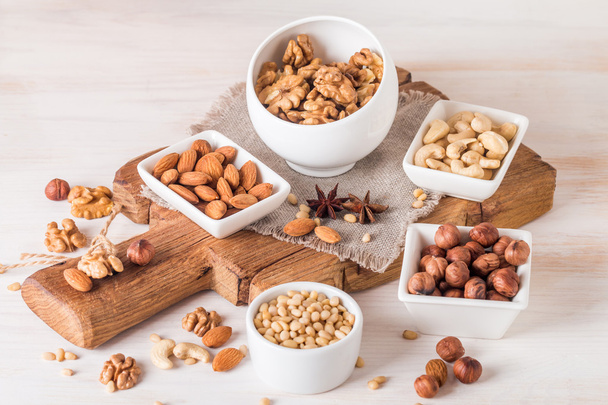 mandle, vlašské ořechy, lískové ořechy kešu a piniové oříšky v dřevěné misce - Fotografie, Obrázek