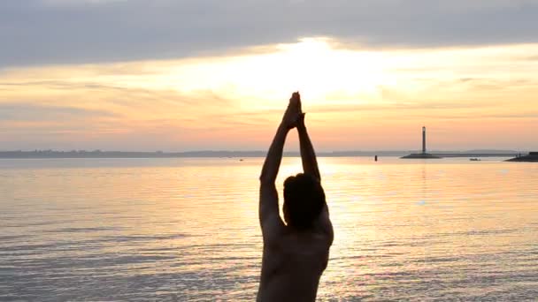 Hombre practicando yoga al amanecer en la playa
 - Metraje, vídeo
