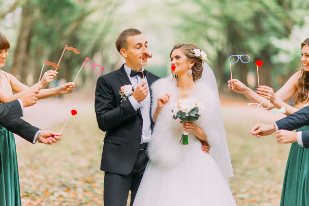 Bella coppia sposata attaccata al viso baffi di carta, occhiali, fiocco
 - Foto, immagini