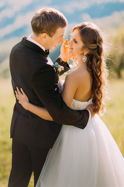 Handsome groom gently touches face of his bride on the nature - Fotografie, Obrázek