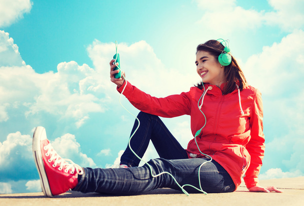 Szczęśliwa młoda kobieta z smartphone i słuchawki - Zdjęcie, obraz