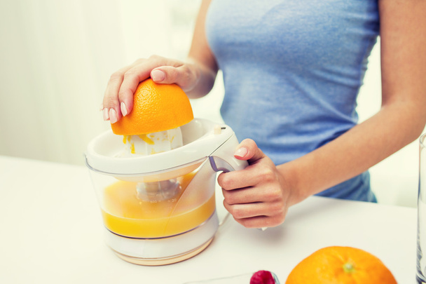 close up of woman squeezing orange juice at home - Фото, изображение