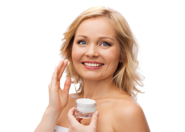 happy woman applying cream to her face - 写真・画像