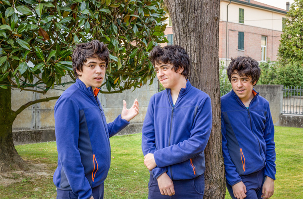 три мальчика разговаривают друг с другом в саду, на самом деле один и тот же парень на фото в многоэтажном городе
 - Фото, изображение