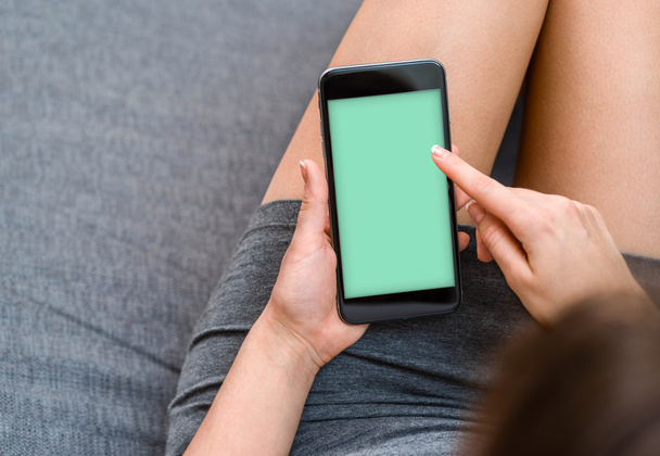 Woman takes a rest with smartphone on sofa.  - Foto, Bild