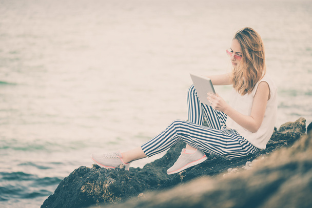 Girl using a digital tablet by the sea. - Photo, Image